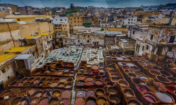 The tannery is located in the heart of the old medina of Fes and is surrounded by a maze of narrow streets and alleys. Visitors can observe the tanning process from the balconies of nearby leather shops, which offer a bird's-eye view of the tannery's vats and workers.
