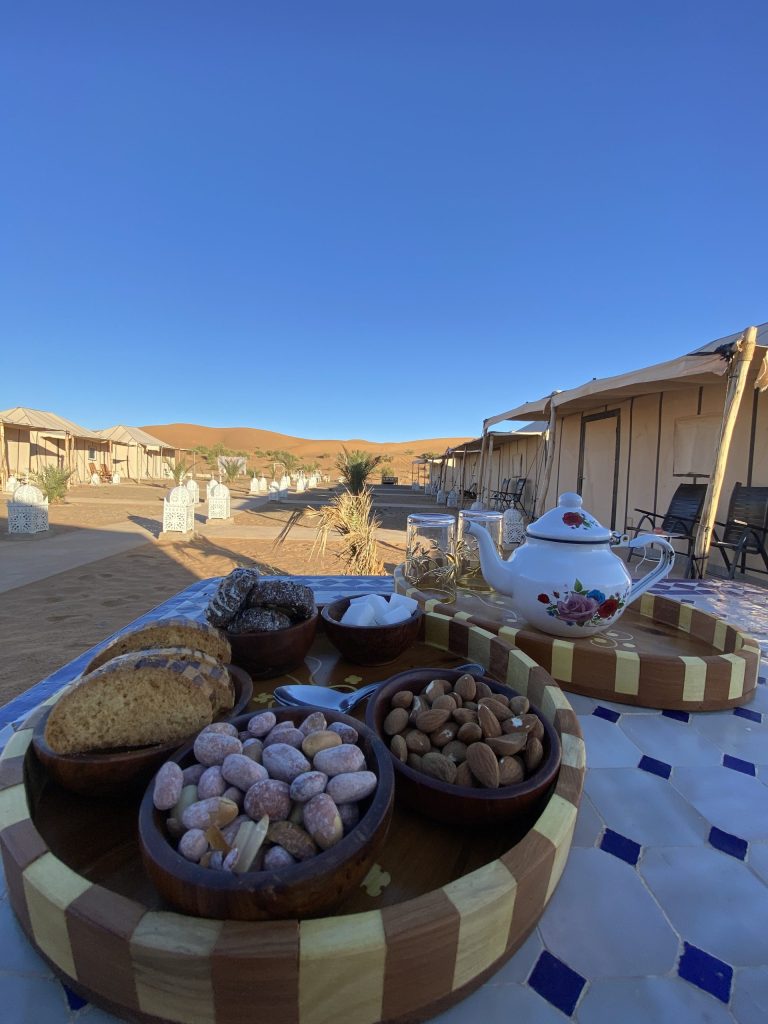 Tea set, nuts and sweets on a table outside Sahara camp tents